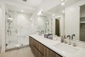 Bathroom featuring a marble finish shower, double vanity, light tile patterned flooring, a walk in closet, and recessed lighting