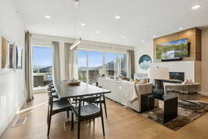 Dining room with a large fireplace, light wood-type flooring, and recessed lighting