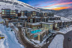 Snowy aerial view with view of pool area, a mountain view, and a residential view