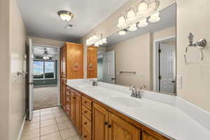 Bathroom with double vanity, light tile patterned flooring, and light carpet