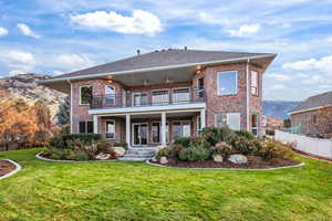Rear view of house featuring a balcony, brick siding, a mountain view, and roof with shingles