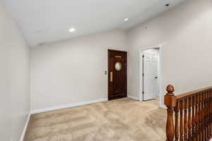 Entryway featuring vaulted ceiling, carpet, and recessed lighting