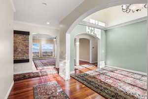 Corridor featuring crown molding, wood finished floors, arched walkways, and recessed lighting