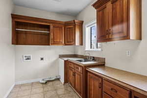 Laundry area with cabinet space, hookup for an electric or gas dryer, light tile  floors