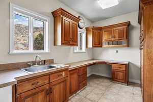Laundry featuring brown cabinets, built in study area, light countertops, and light tile  floors