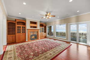 Living room with ornamental molding, a fireplace, dark wood-style flooring, ceiling fan, and recessed lighting