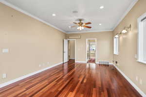 Master suite with molding, dark wood-style floors, recessed lighting, ceiling fan, and a wall unit AC