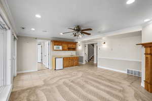 Wet bar/kitchen featuring light countertops, light tile patterned floors, brown cabinetry, ornamental molding, and ceiling fan