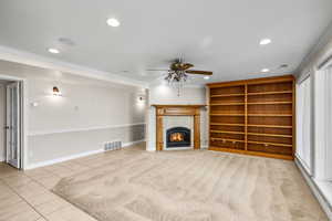 Unfurnished living room with recessed lighting, crown molding, light tile patterned floors, ceiling fan, and a tiled fireplace