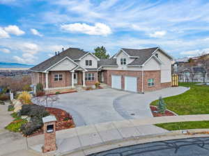 View of front of home with concrete driveway, a garage, brick siding, a shingled roof, and stucco siding