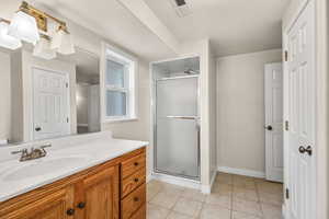 Bathroom with a shower stall, vanity, and light tile patterned flooring