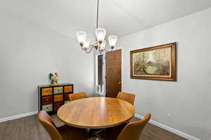 Dining space with wood finished floors and a chandelier