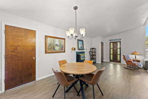 Dining area featuring light wood-style floors, a chandelier, and lofted ceiling