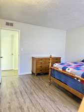 Bedroom with wood finished floors and a textured ceiling
