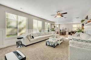 Carpeted living area with a wainscoted wall and a ceiling fan