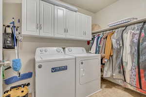 Washroom with separate washer and dryer, light tile patterned floors, and cabinet space