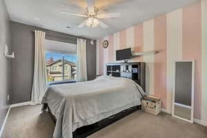 Carpeted bedroom featuring ceiling fan and baseboards