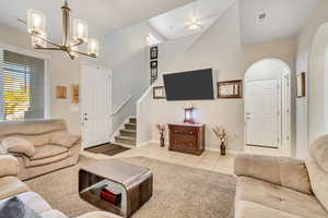 Living room with light tile patterned floors, stairway, a chandelier, and light colored carpet