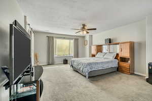 Bedroom with carpet flooring, a textured ceiling, and a ceiling fan