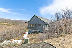 View of property exterior with roof with shingles and a mountain view