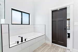 Full bath featuring wood finish floors and a garden tub