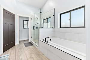 Full bath with a garden tub, a stall shower, and light wood-type flooring