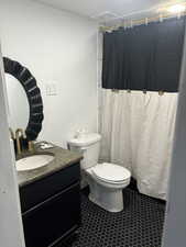 Full bathroom featuring curtained shower, vanity, and dark tile patterned flooring