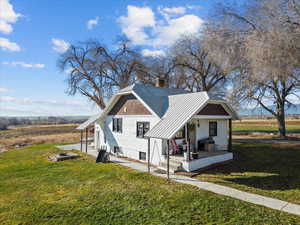 View of home's exterior with covered porch, a metal roof, a yard, and a chimney