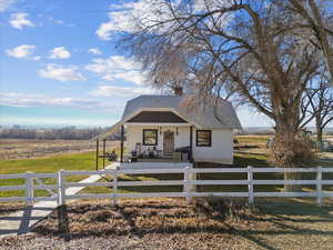 Bungalow featuring a porch, a view of rural / pastoral area, a fenced front yard, and a chimney