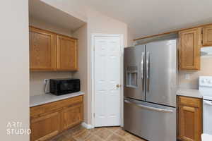 Kitchen featuring stainless steel refrigerator with ice dispenser, light countertops, electric range, black microwave, and a textured ceiling
