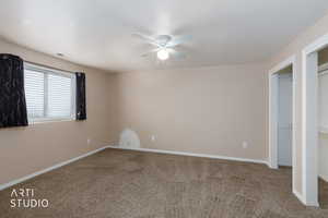 Unfurnished bedroom featuring carpet flooring, ceiling fan, a textured ceiling, and multiple closets