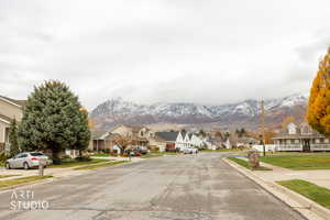 View of asphalt street featuring sidewalks, a mountain view, curbs, and a residential view