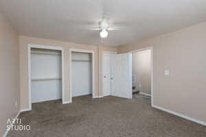 Unfurnished bedroom with two closets, carpet floors, a textured ceiling, and ceiling fan