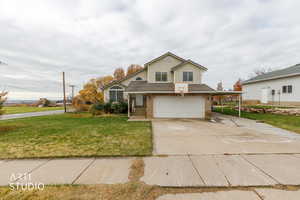Traditional home featuring driveway, brick siding, roof with shingles, a front lawn, and a garage