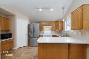 Kitchen featuring light countertops, a peninsula, stainless steel refrigerator with ice dispenser, decorative light fixtures, and electric stove
