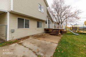 View of side of home with a trampoline, a patio area, a lawn, and a deck