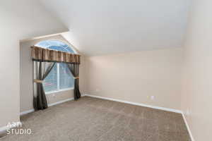 Additional living space featuring light colored carpet and lofted ceiling