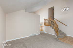 Stairway featuring carpet flooring, vaulted ceiling, tile patterned flooring, and a chandelier