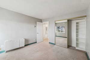 Unfurnished bedroom featuring carpet, a textured ceiling, and a closet