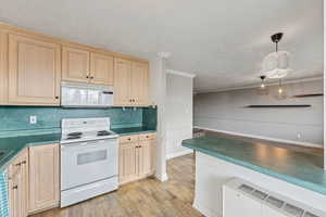 Kitchen featuring white appliances, dark countertops, light brown cabinets, pendant lighting, and a textured ceiling