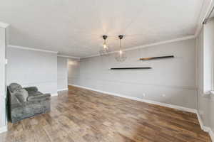 Unfurnished room featuring ornamental molding, a textured ceiling, and wood finished floors