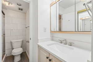 Bathroom with vanity, dark wood finished floors, tile walls, and a stall shower