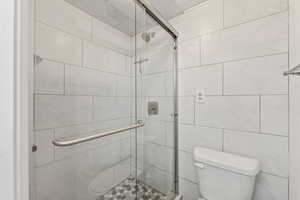 Full bathroom featuring a stall shower and toilet