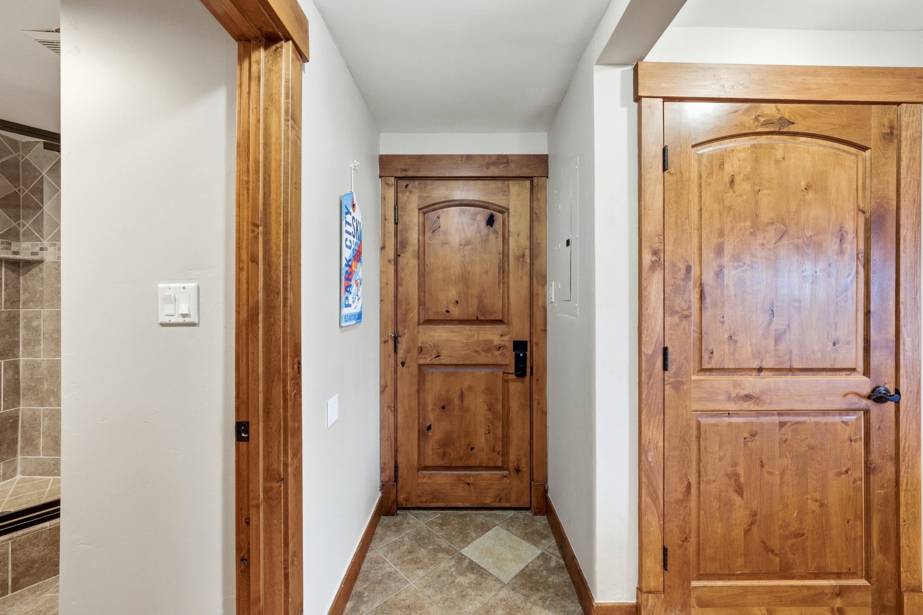 Hallway featuring wood-finish doors with arched panels and dark hardware