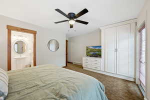Bedroom with dark carpet, a ceiling fan, baseboard heating, a closet, and ensuite bath