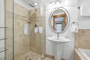 Bathroom with a stall shower and a relaxing tiled tub