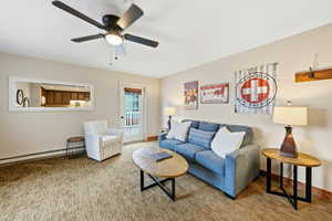 Living room with a baseboard radiator, carpet flooring, and ceiling fan