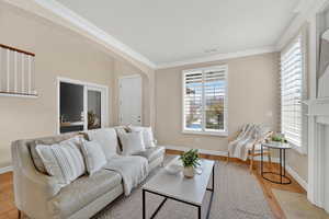 Living area with crown molding, wood finished floors, and arched walkways