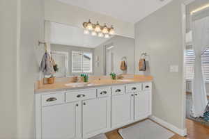Bathroom with double vanity and light wood-type flooring