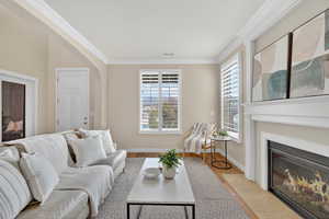Living area featuring crown molding, arched walkways, and a fireplace with flush hearth